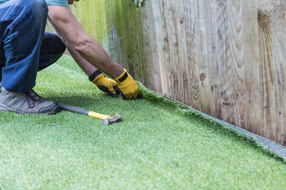 Artificial Grass Being Installed - The Installer Has a Hammer and Nails