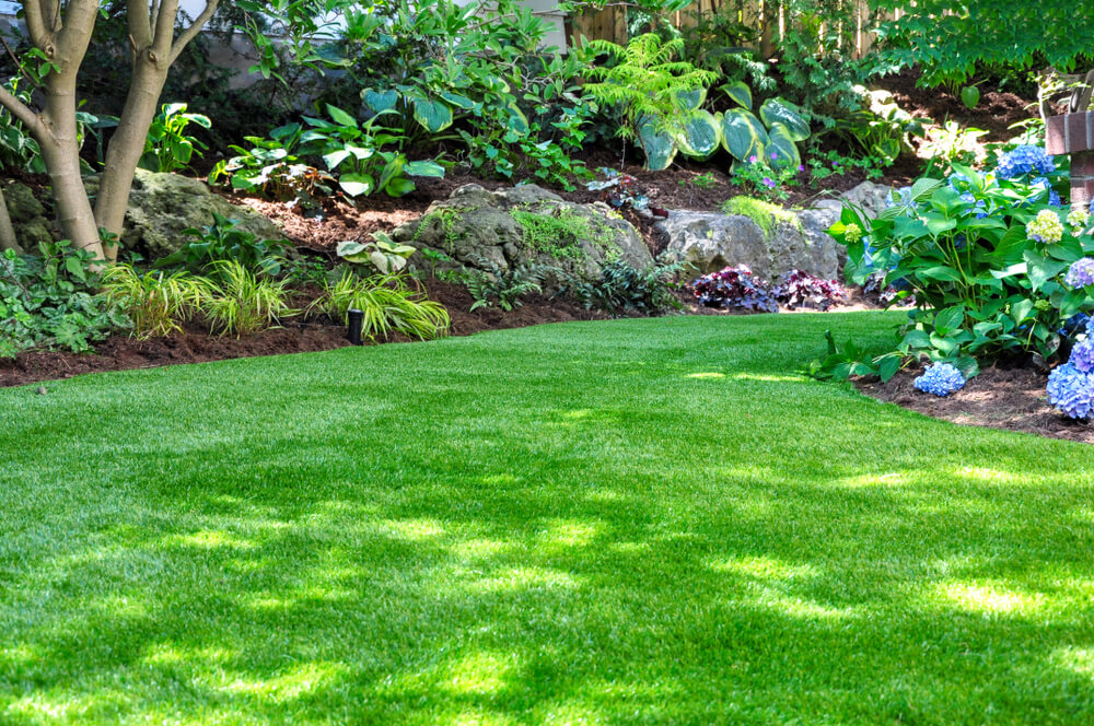 Beautiful Backyard Woodland Garden Features a Maintenance Free Lawn Made of Realistic Looking Artificial Grass