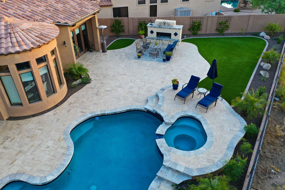 A 4K High Resolution Aerial View of a Pool and Spa With a Travertine Patio and Outdoor Fireplace.