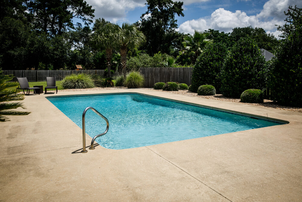 Residential Backyard Swimming Pool in the Suburbs With a Landscaped Backyard and a Fence.
