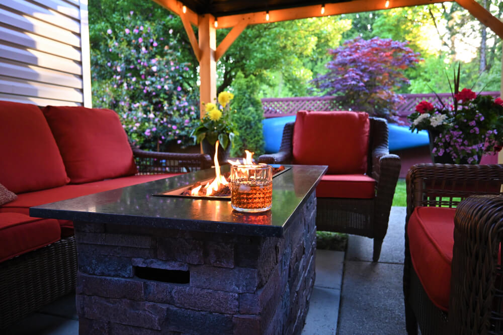 Outdoor Patio Set With a Gas Fireplace a Glass of Scotch Whiskey on Ice and Potted Flowers Under a Gazebo