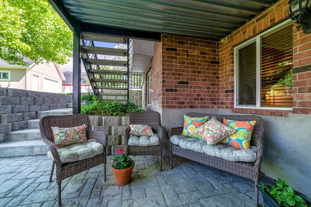 Outdoor Patio Under a Deck With Woven Lounge Chairs and Potted Plants