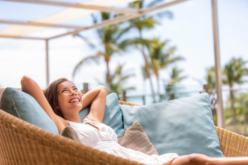 A woman relaxing on a sofa furniture of outdoor patio.