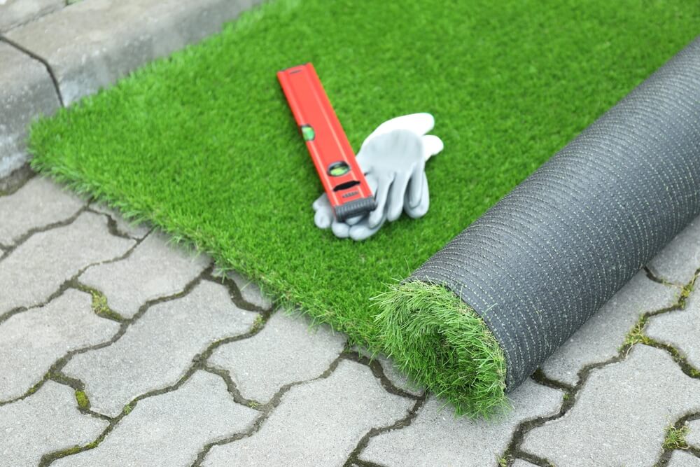 Gloves, level tool and roll of artificial turf.